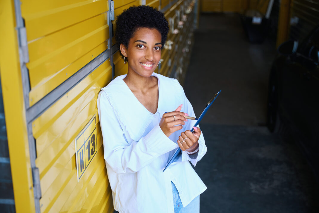 woman stands in self storage facility with tablet and pen