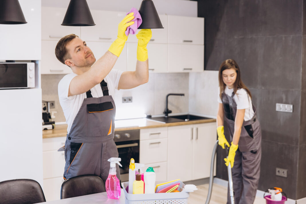 Cleaning company employees cleaning kitchen appliances and floor